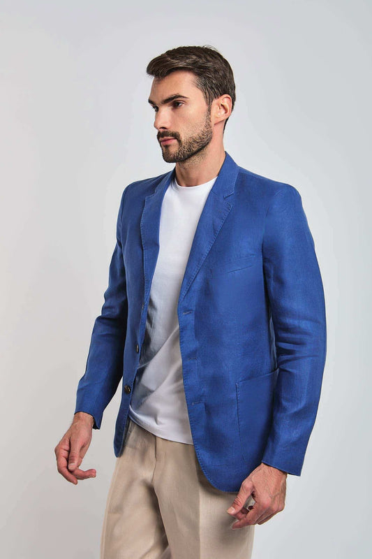 Man wearing a blue blazer, white t-shirt, and beige pants on a plain background