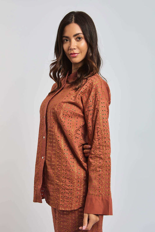 Woman wearing an orange embroidered button-up shirt with eyelet detailing