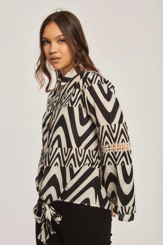 Woman wearing Dalydress black and white geometric print blouse with tie waist and cutout sleeve