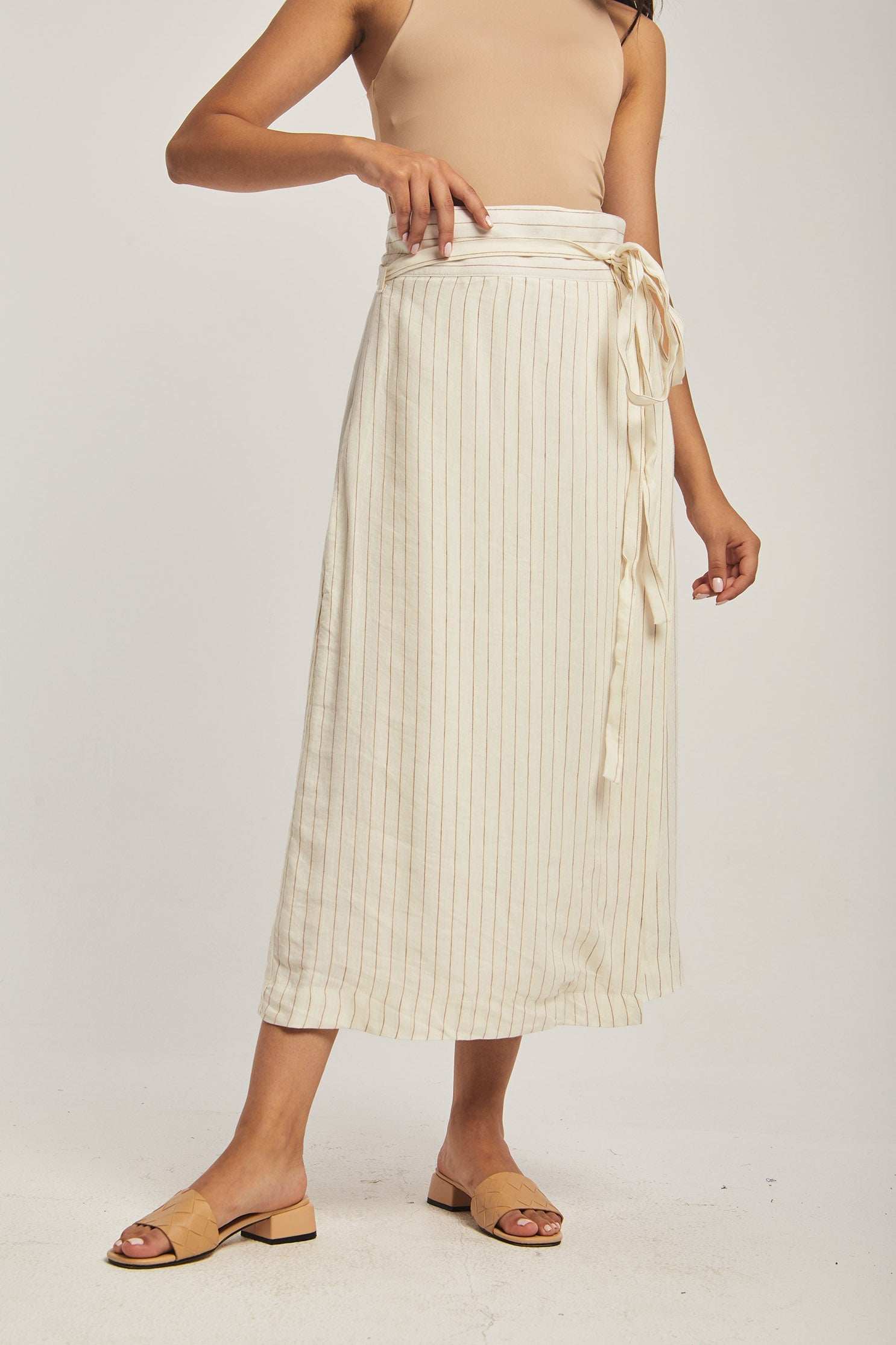 Woman wearing Dalydress beige tank top and cream pinstripe wrap midi skirt with tie waist