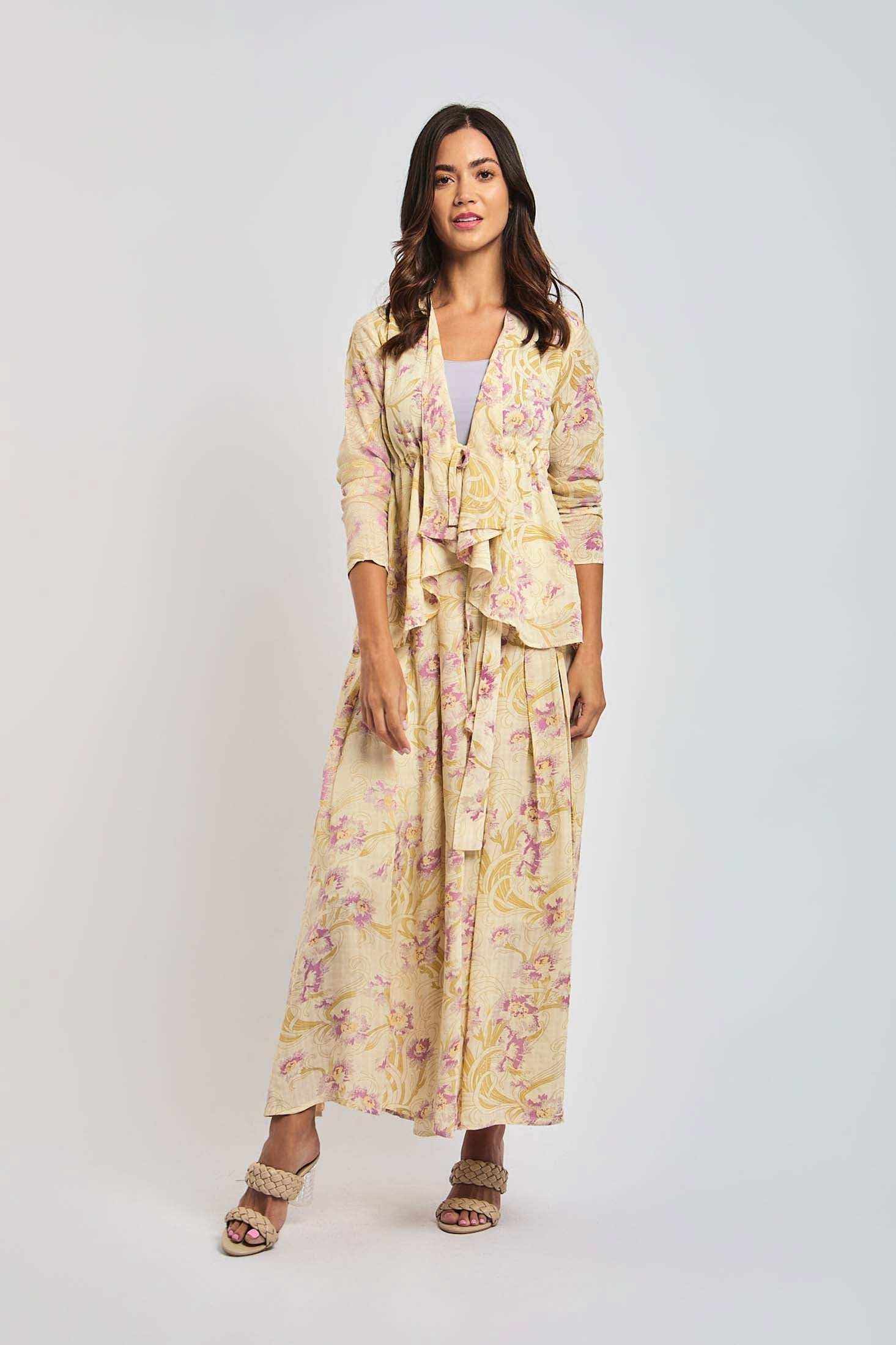 Woman wearing a long, floral yellow and pink Dalydress outfit with ruffled jacket