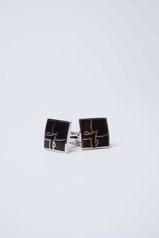 Square black and silver cufflinks with geometric design on white background