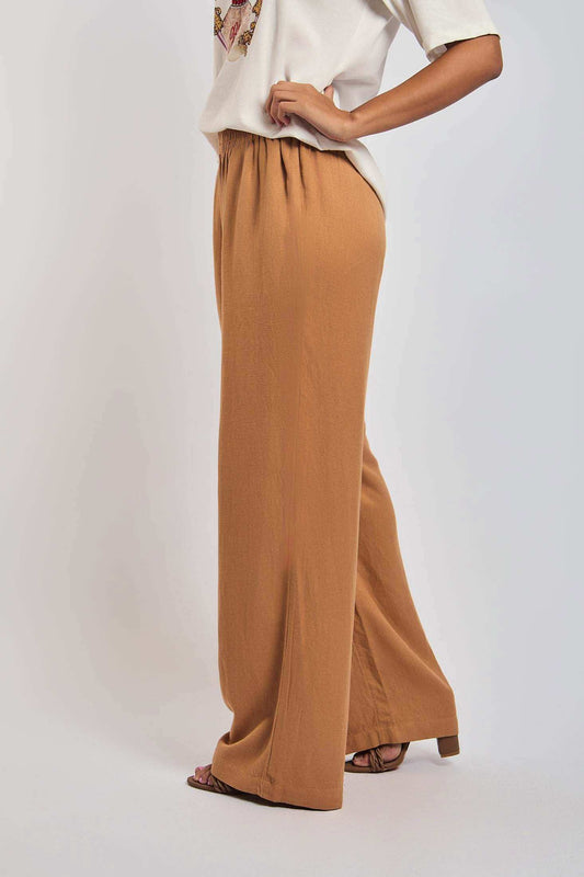 Woman wearing loose fit brown wide leg pants and white graphic t-shirt, side view