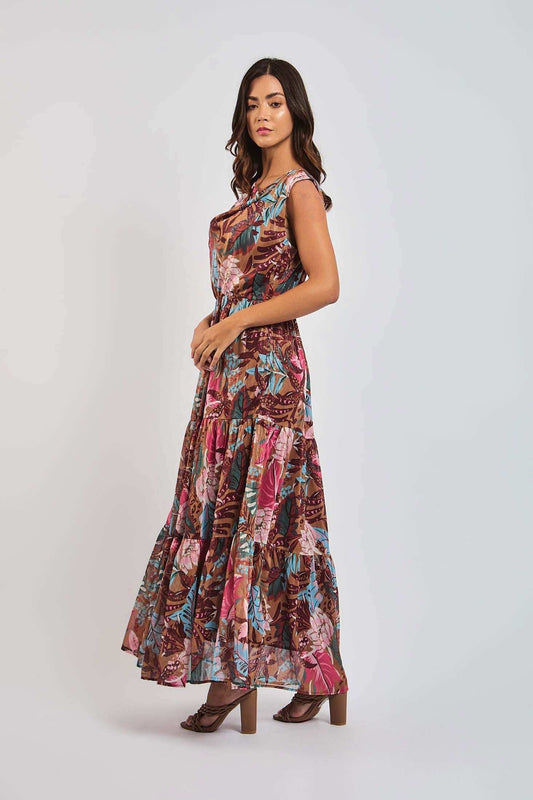 Woman wearing a sleeveless floral maxi dress with brown, pink, and blue tropical print
