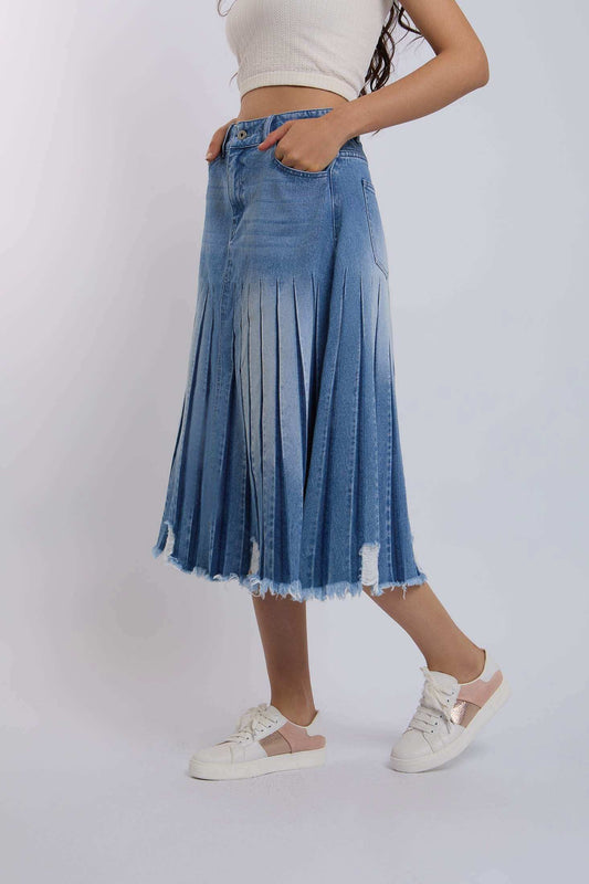 Woman wearing pleated denim midi skirt with frayed hem and casual sneakers on white background