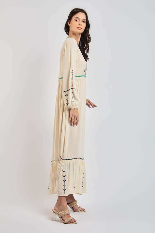 Woman in cream embroidered maxi dress with long sleeves and braided heeled sandals