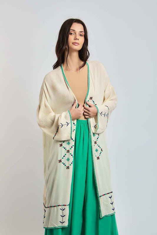 Woman wearing cream embroidered cardigan over green dress, modern casual fashion