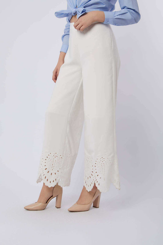 Woman wearing white wide-leg pants with lace hem, light blue blouse, and nude heels