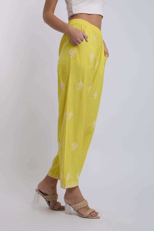Woman wearing yellow embroidered loose pants with pockets and heeled braided sandals