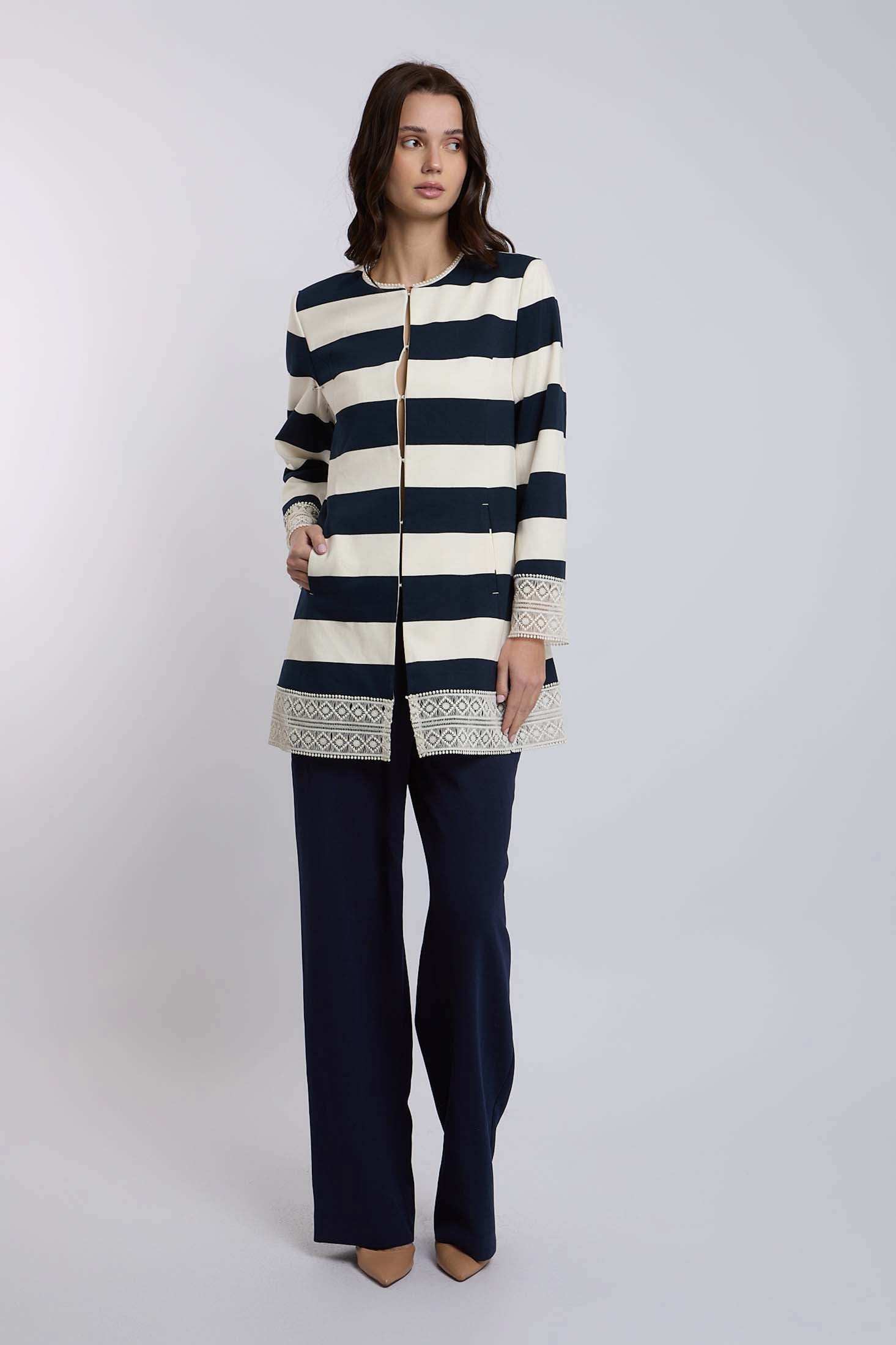 Woman wearing Dalydress navy and cream striped jacket with embroidered trim and navy pants.
