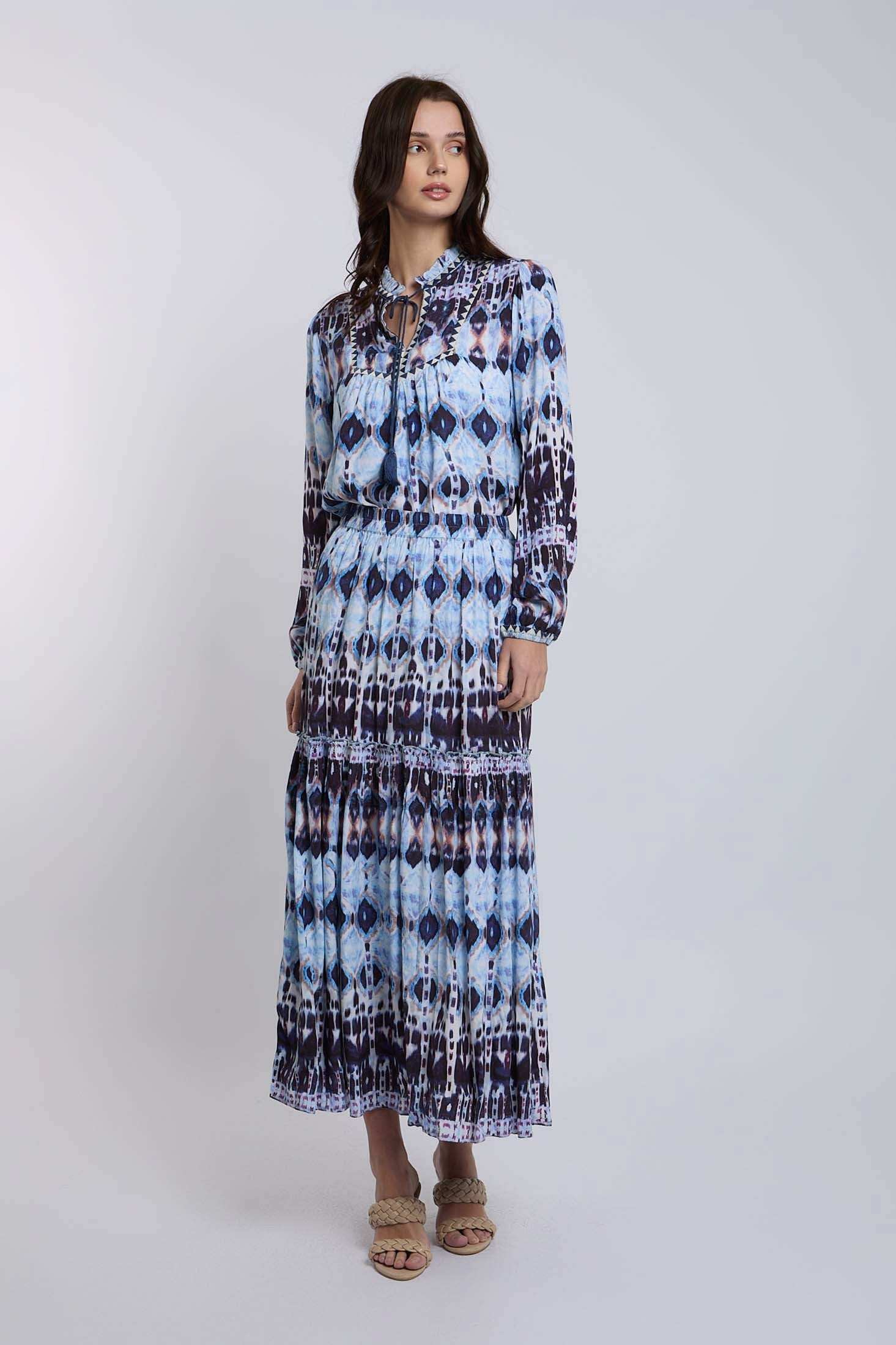 Woman wearing a long sleeve blue and white patterned maxi dress with braided sandals