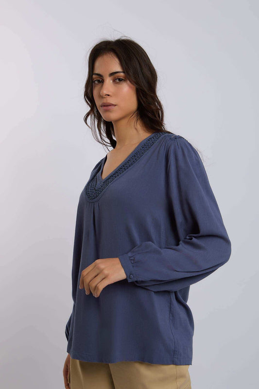 Woman wearing blue long sleeve V-neck blouse with embroidered trim