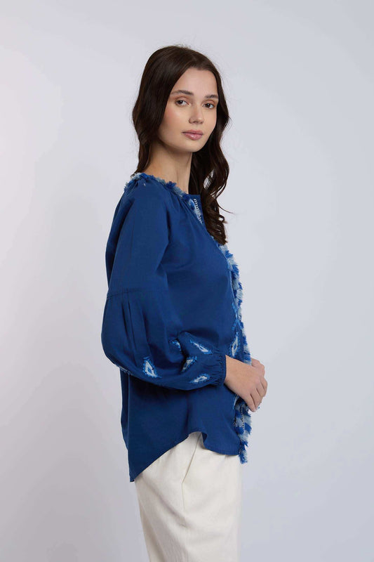 Woman in blue long-sleeve blouse with frayed trim and white pants, casual fashion