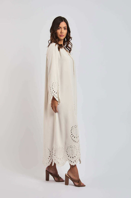 Woman in cream long dress with laser-cut floral hem and sleeves, block heel sandals