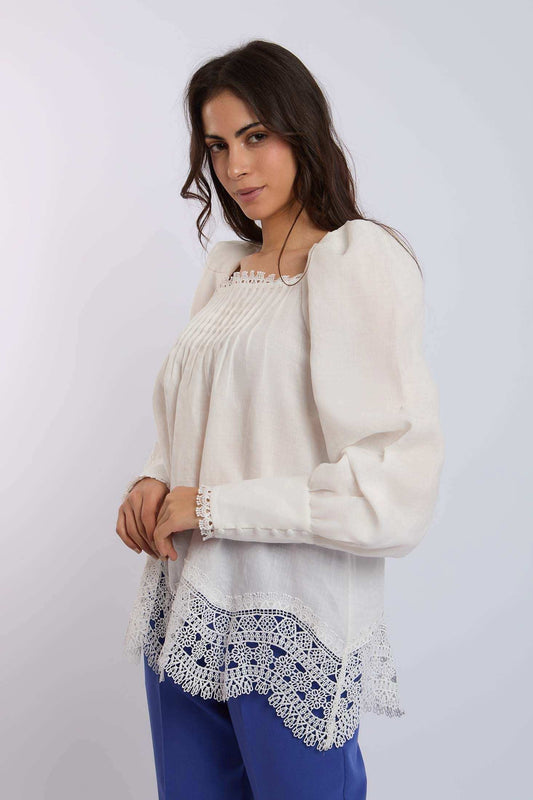 Woman wearing a white long sleeve blouse with lace trim and blue pants