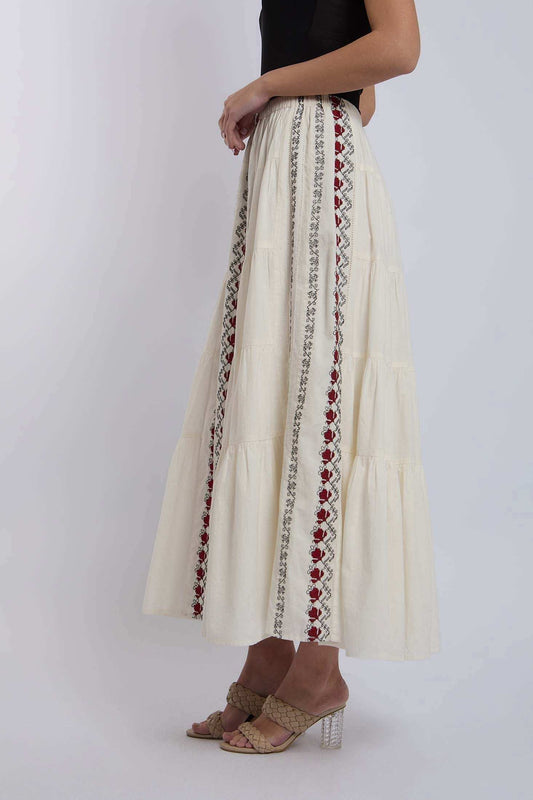 Woman wearing cream maxi skirt with red and black embroidered vertical patterns