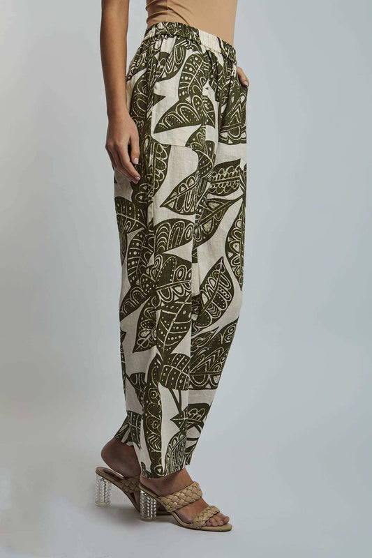 Woman wearing high-waisted beige and green leaf print pants with heeled sandals
