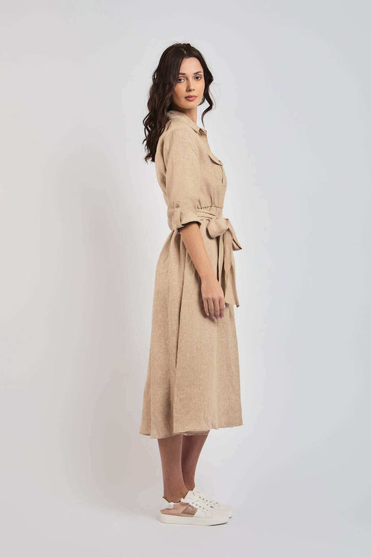 Woman in beige midi shirt dress with tie waist and rolled sleeves, casual sneakers, studio background