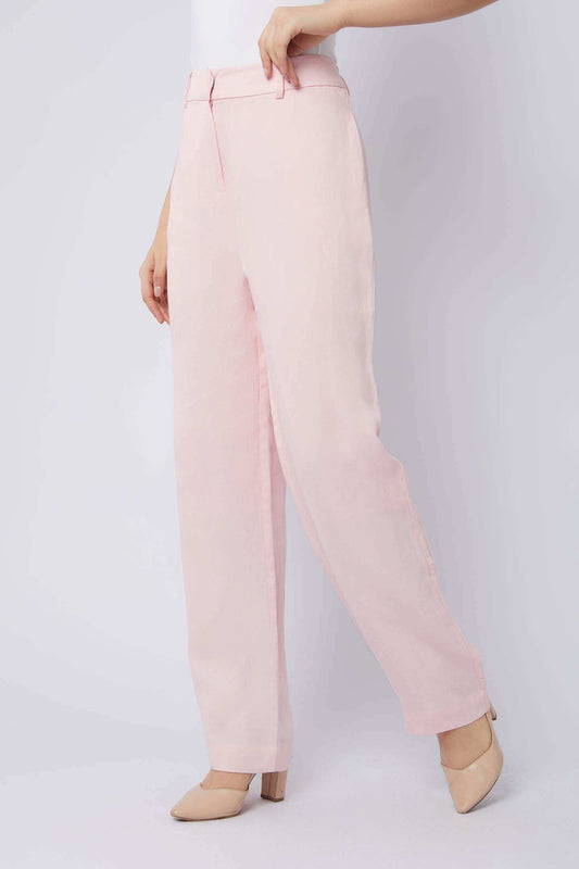 Woman wearing light pink wide-leg trousers with beige heels on white background