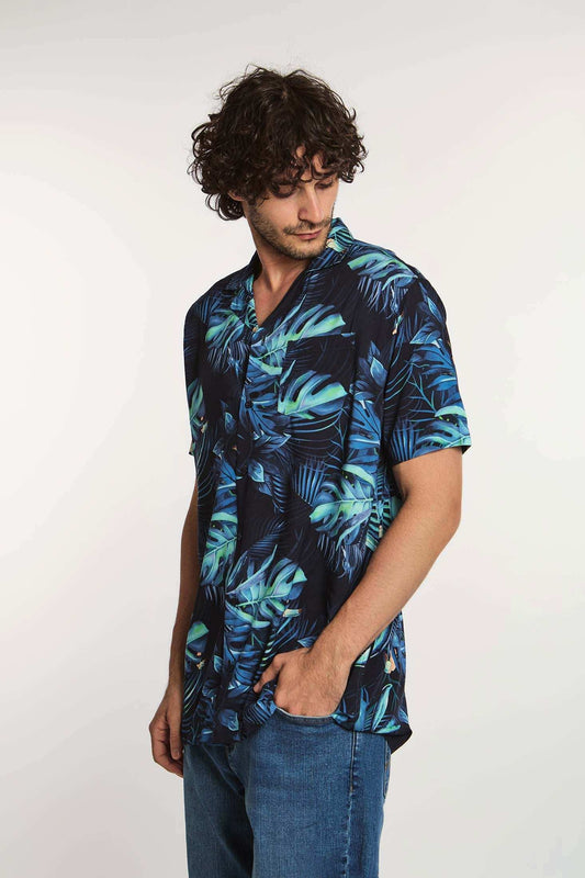 Man wearing short-sleeve navy tropical leaf print shirt and blue jeans