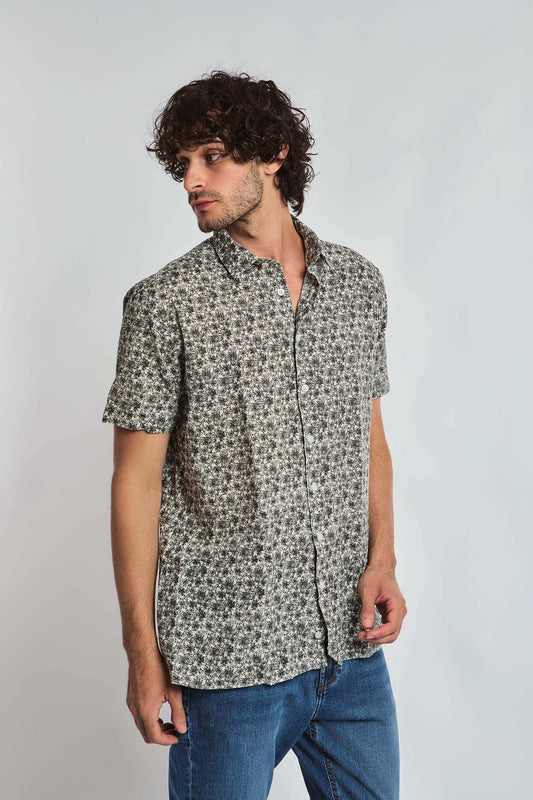 Man wearing a short sleeve floral print shirt and blue jeans, casual menswear