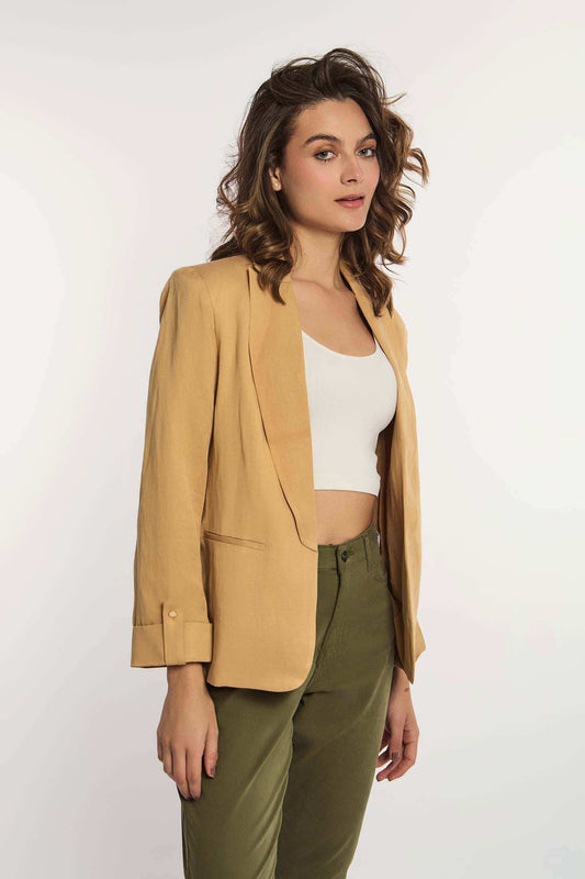 Woman in mustard yellow blazer, white crop top, and olive green pants on white background