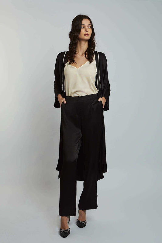 Woman wearing a cream blouse, black long cardigan, and black wide-leg trousers