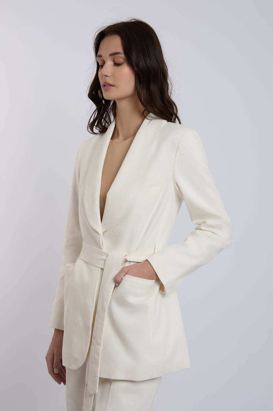 Woman wearing a white belted blazer with long sleeves and tailored fit